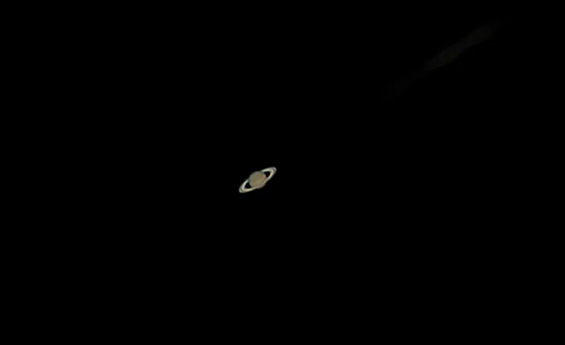 Saturn mit Ringen, klein im dunklen Gesichtsfeld eines Amateurteleskops