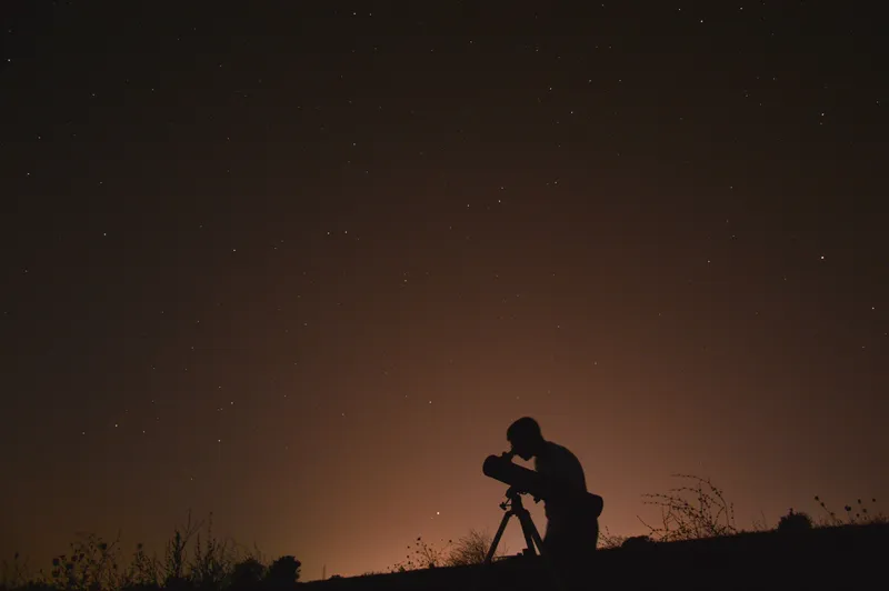 Silhouette am Teleskop unter dem Sternenhimmel